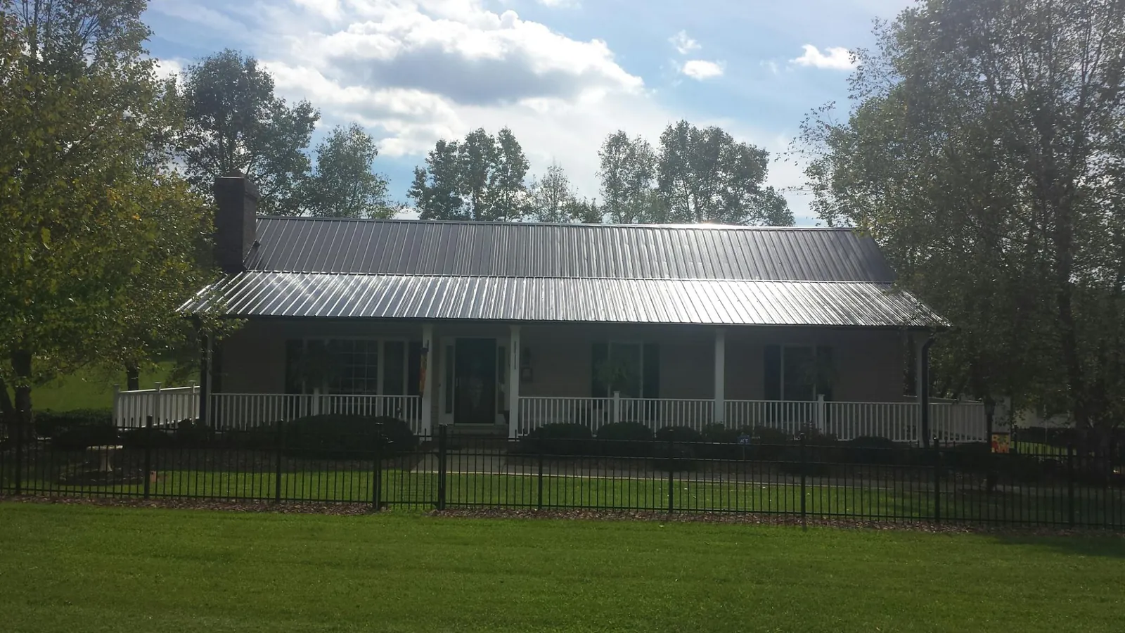Gray metal roof on a brick ranch with a full width front porch — Gutter Guard Installation work by our crew in Martinsdale