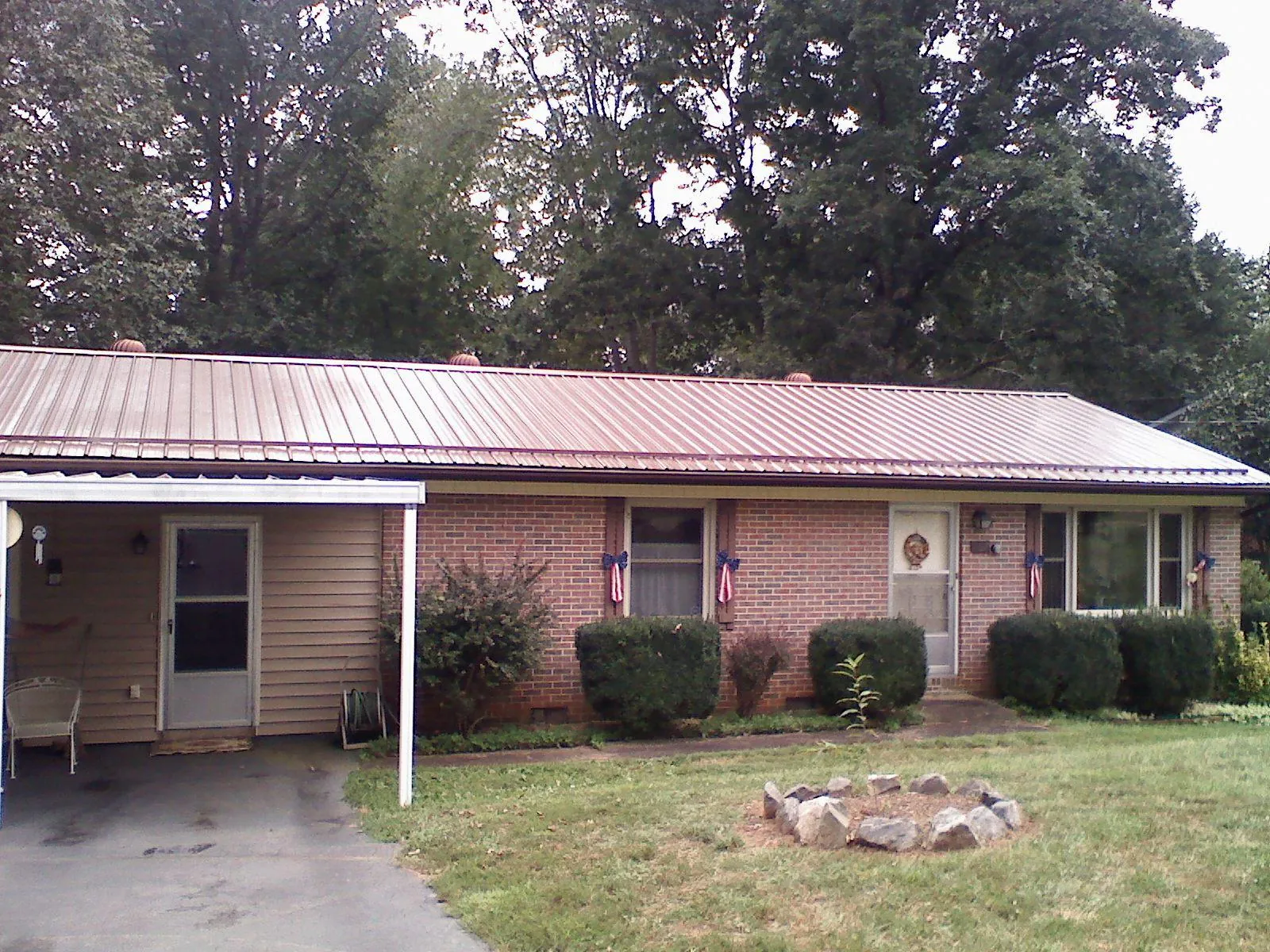Bronze metal roof and carport on a brick ranch home — Roof Repair work by our crew in Martinsdale