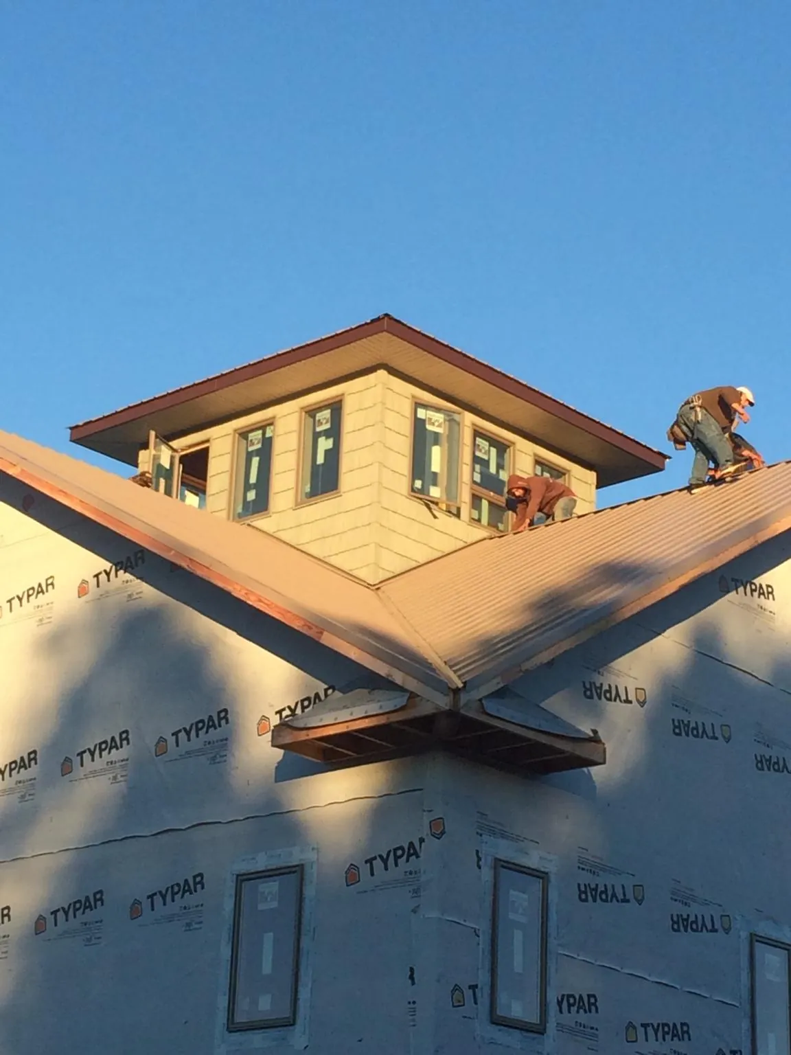 Roofers working around a rooftop cupola on a new metal roof at sunset — Roof Waterproofing in Martinsdale by Roofing Brothers